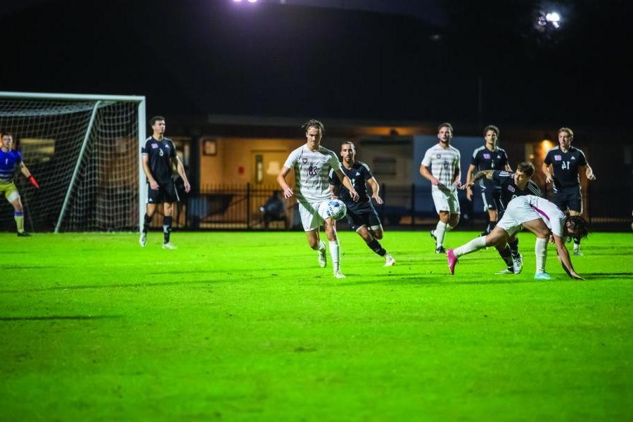 men's soccer players run for ball